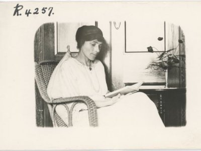 woman sits in a wicker chair reading a book